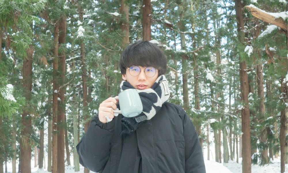 雪の杉林でマグカップを手にする井上志音
