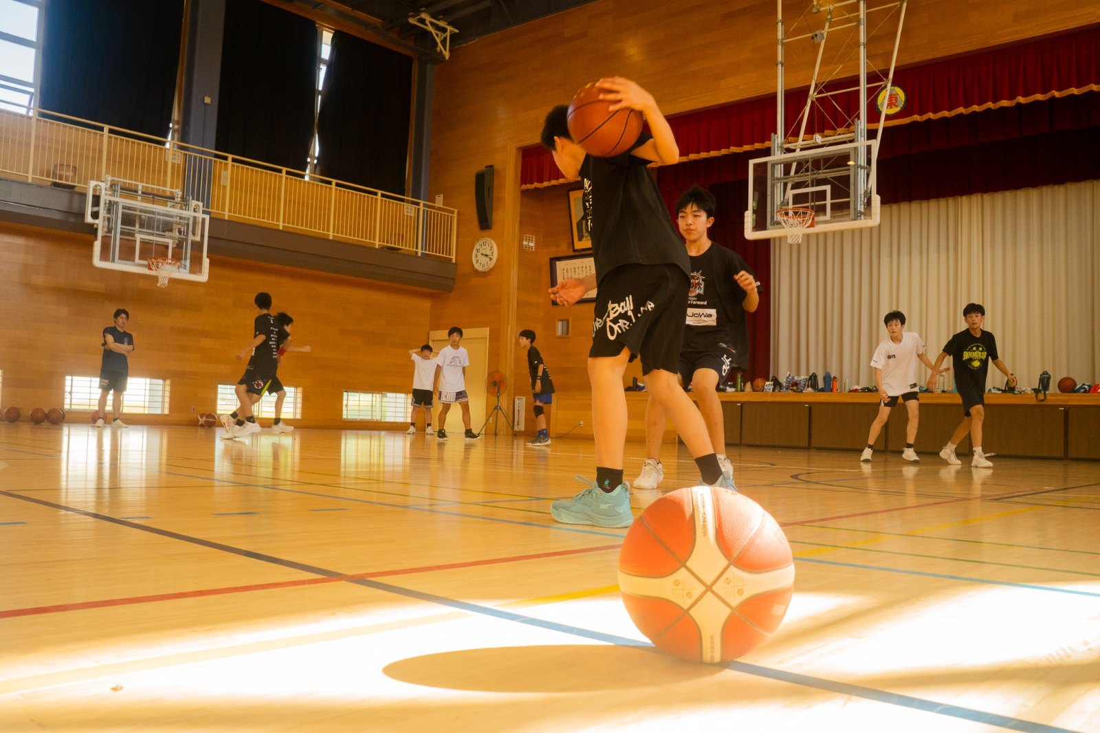 体育館でバスケットボールをドリブルしようとする選手